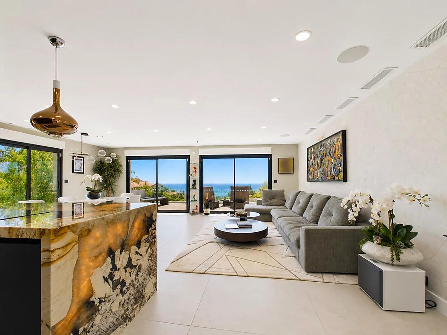 Living and dining room with full-height sliding windows opening to the sea view