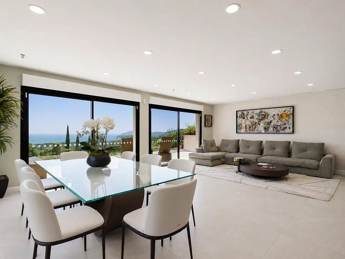 Dining table and living room with the sea framed by sliding windows