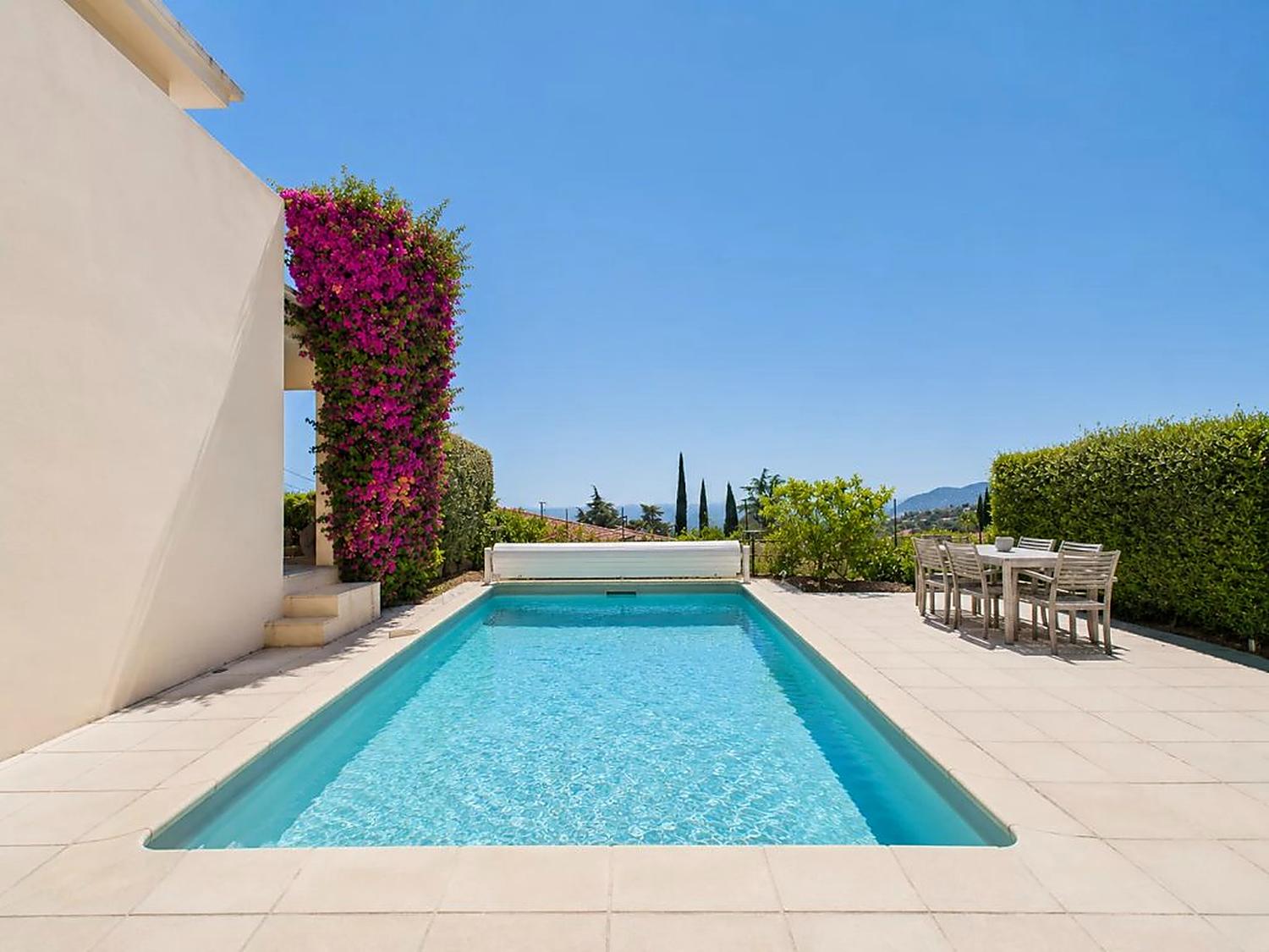 Swimming pool with bougainvillea and a shaded dining table